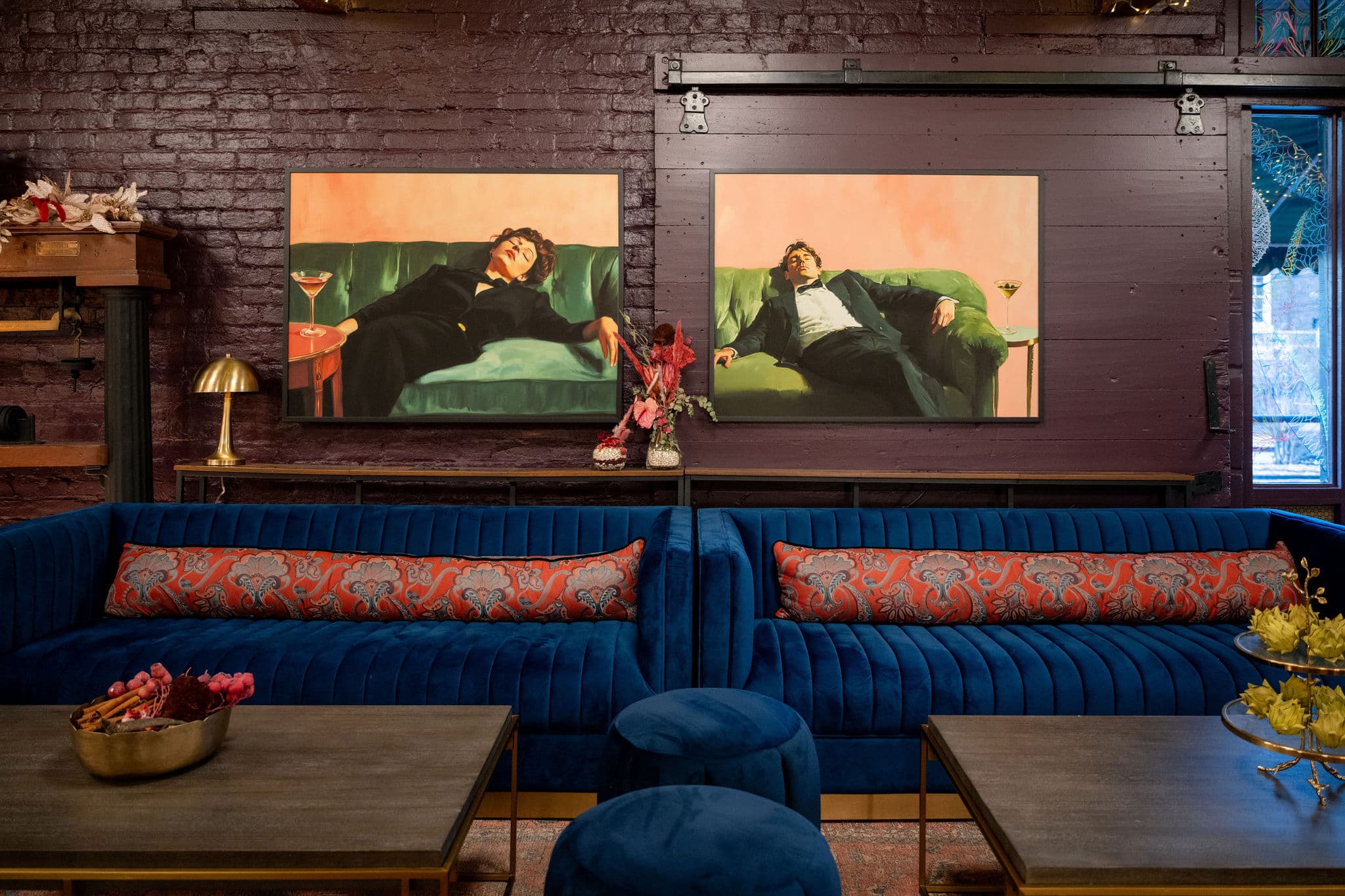 Blue velvet sofa beneath gallery wall paintings